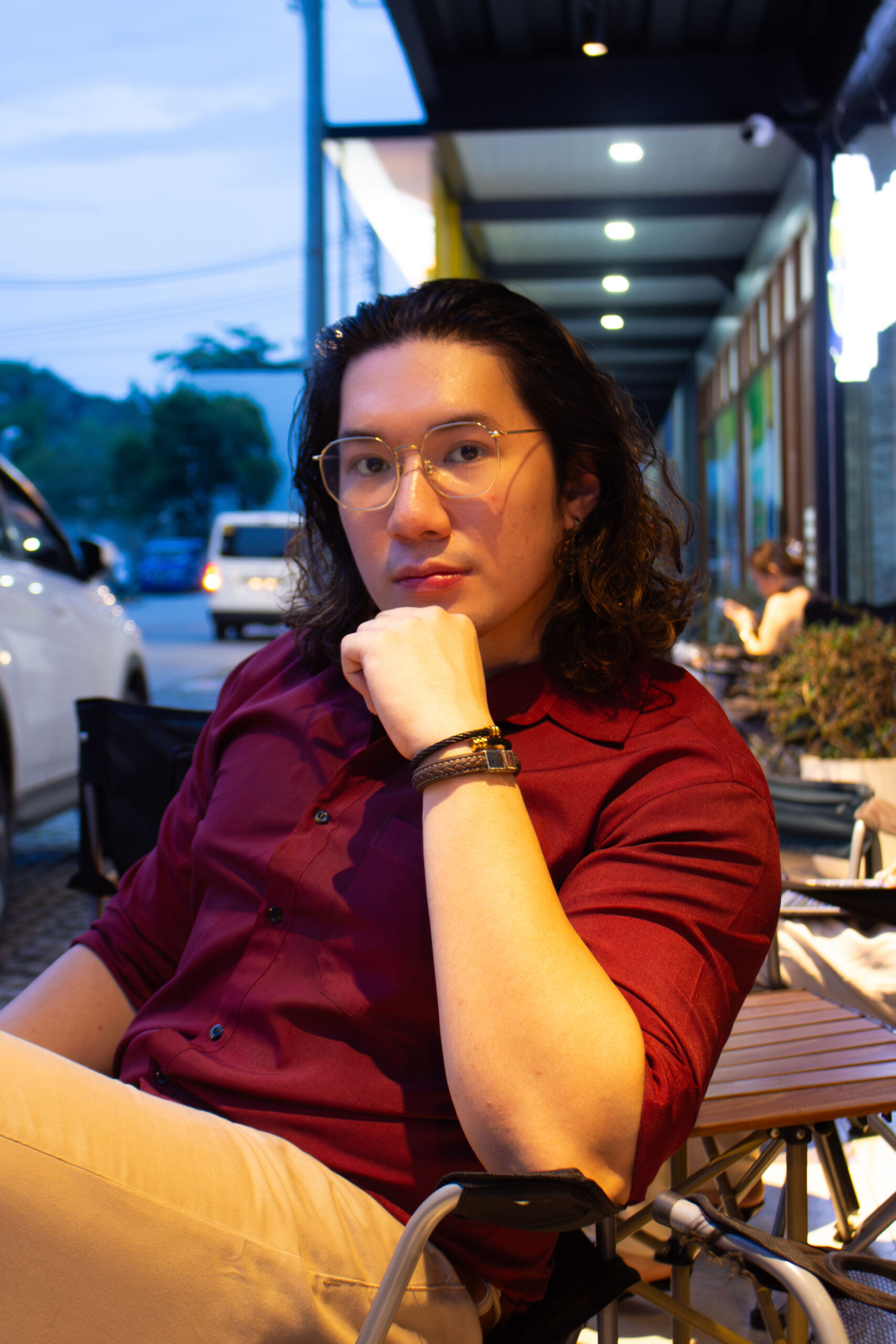Liam at an outdoor café at dusk, chin resting on his hand